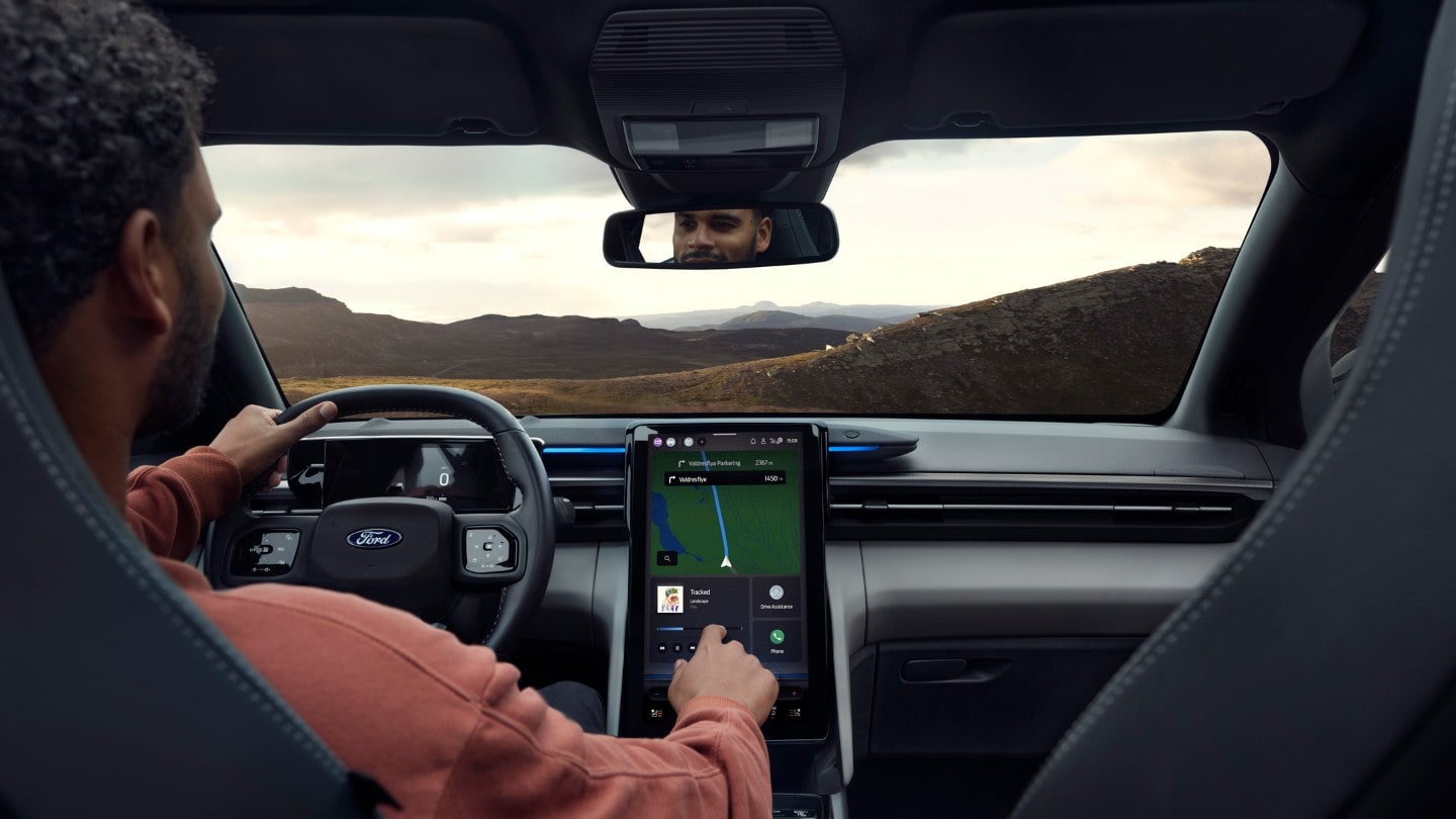 Interior view of a Ford Explorer, showing a person driving with the dashboard and center console display visible.