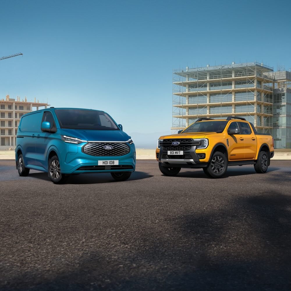  A blue Ford Transit Custom van and an orange Ford Ranger parked in front of buildings under construction.