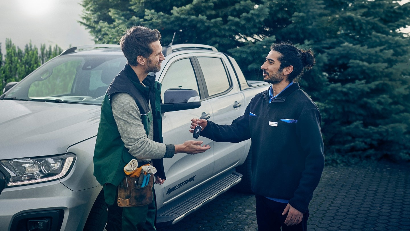 One man is giving car keys to the other one