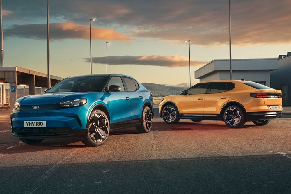 Blue and yellow Ford Capri electric SUVs parked at sunset.