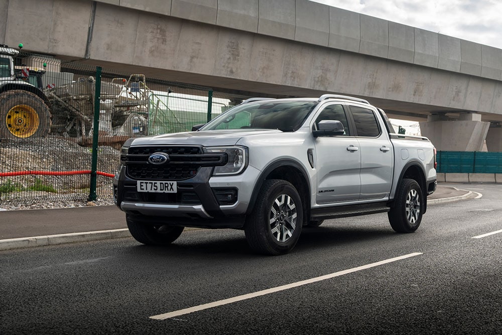 A silver Ford Ranger driving beside a construction site, seen from the front three-quarter angle.