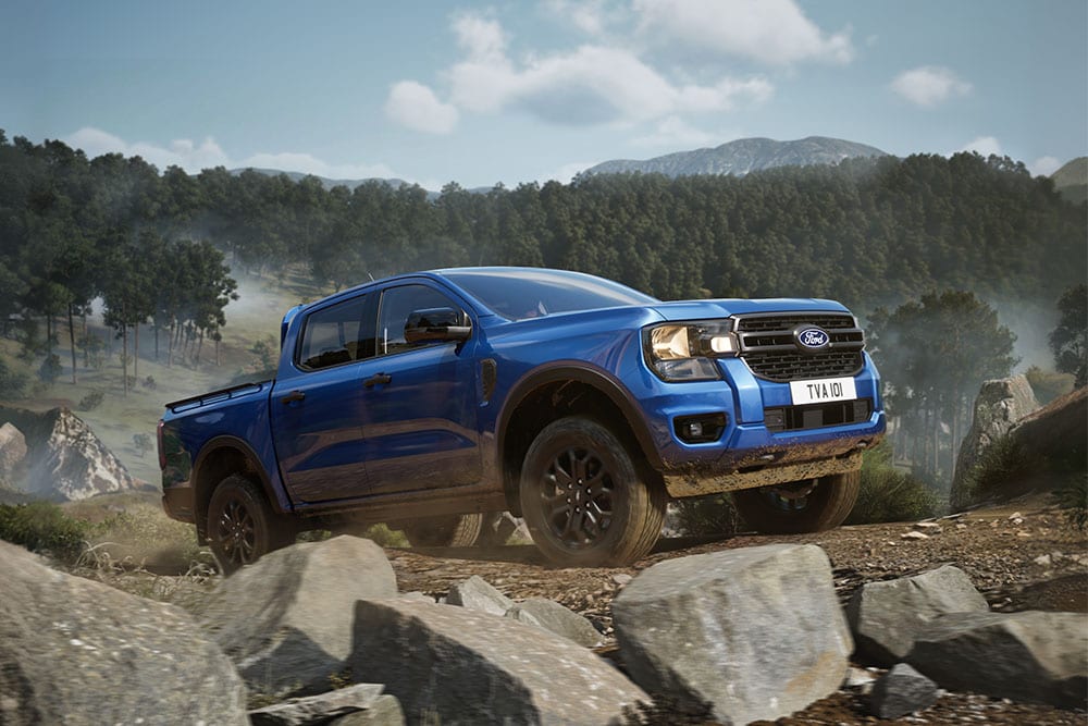 A blue Ford Ranger driving up a steep hill coming out of a forest.