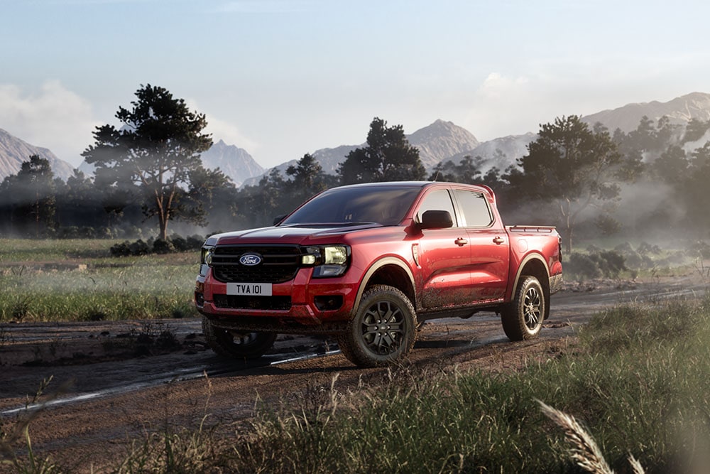 A red Ford Ranger stationary on a mountain road, seen from a front three-quarter angle.