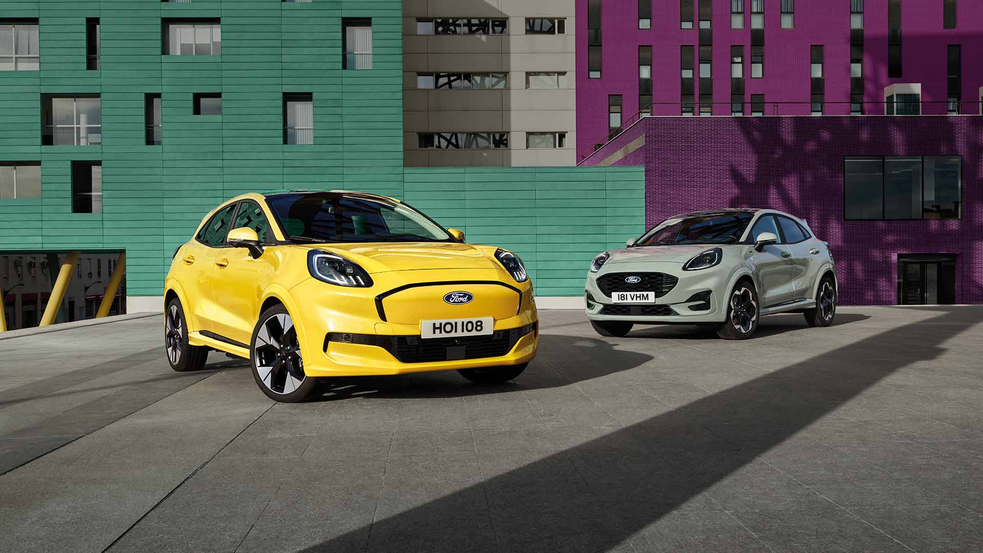 Ford Puma and Ford Puma Gen-E, parked in front of colourful buildings in an urban setting.